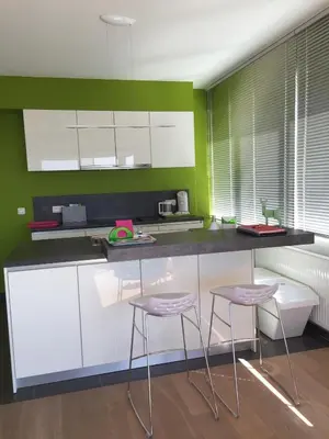 a kitchen with white cabinets and pink stools at Scheldepunt in Ghent