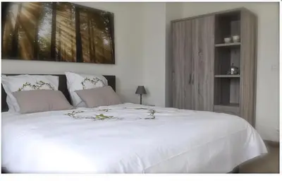 a bedroom with a large white bed with a cabinet at de minnetuin in Wachtebeke