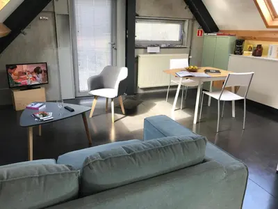 a living room with a couch and a table and chairs at Rap 'n Holiday Home in Sint-Denijs-Westrem