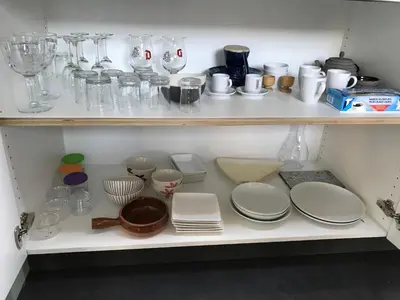 a shelf filled with plates and glassware in a kitchen at Rap 'n Holiday Home in Sint-Denijs-Westrem