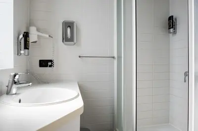 a white bathroom with a sink and a shower at a&o Antwerpen Centraal in Antwerp