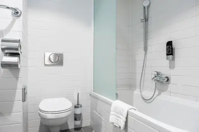 a white bathroom with a toilet and a shower at a&o Antwerpen Centraal in Antwerp