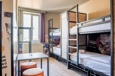 a room with bunk beds with a table and stools at a&o Antwerpen Centraal in Antwerp