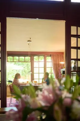 two people sitting at a table in a living room at B&B De Gilleminus in Temse