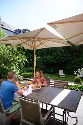 a man and woman sitting at a table under an umbrella at B&B De Gilleminus in Temse