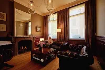 a man sitting on a couch in a living room with a fireplace at B&B De Gilleminus in Temse