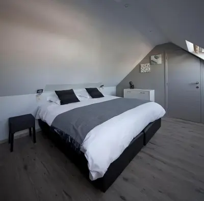 a bedroom with a large bed with white and black sheets at Sino in Dendermonde