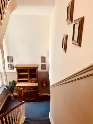 a hallway with a staircase with a dresser and a desk at Hotel Du Parlement in Brussels