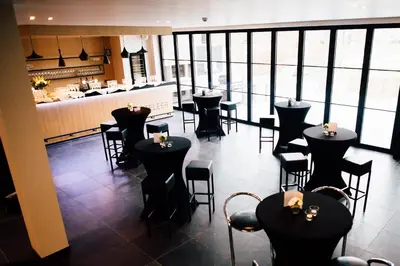 a restaurant with black tables and chairs and a bar at Guesthouse De Casteleer in Kasterlee