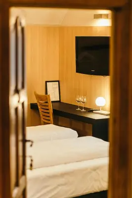 a hotel room with two beds and a desk with a television at Guesthouse De Casteleer in Kasterlee