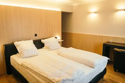 a bedroom with a large bed with white sheets and pillows at Guesthouse De Casteleer in Kasterlee