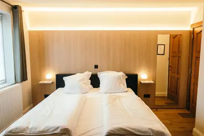 a bedroom with a large bed with white sheets and pillows at Guesthouse De Casteleer in Kasterlee