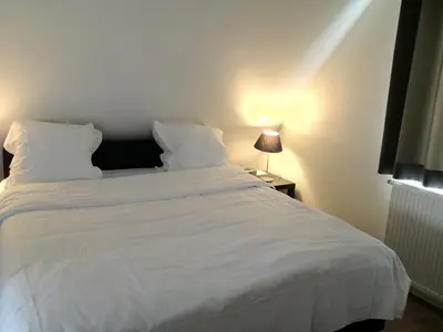 a bedroom with a white bed with a white blanket at Guesthouse De Casteleer in Kasterlee