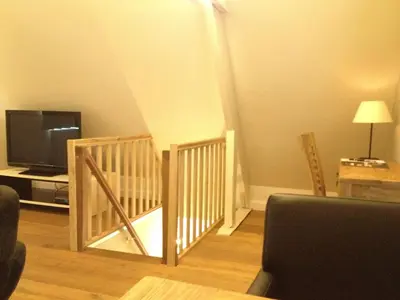 a living room with a staircase with a tv and a couch at Guesthouse De Casteleer in Kasterlee