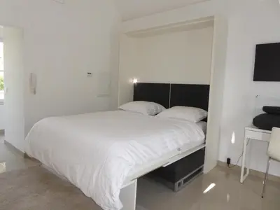 a white bedroom with a large bed and a desk at B&B Goudvink in Schilde