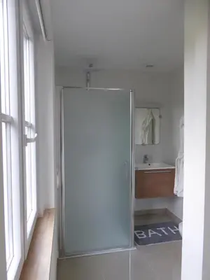 a glass shower door in a bathroom with a sink at B&B Goudvink in Schilde