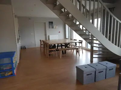 a dining room with a table and a staircase at De Schaapskooi in Kasterlee