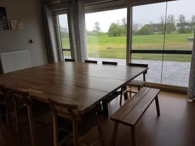 a wooden table and chairs in a room with a large window at De Schaapskooi in Kasterlee