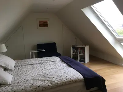 a bedroom with a bed and a chair in a attic at B&B Wannes Suite in Leuven