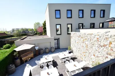 a patio with white tables and chairs and a building at Atelier 24 in Sint-Pieters-Leeuw