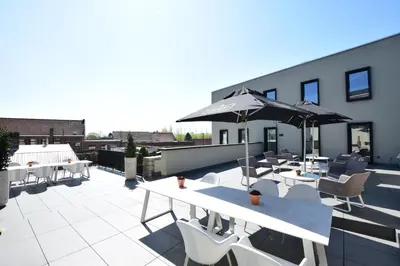 a patio with tables and chairs and an umbrella at Atelier 24 in Sint-Pieters-Leeuw