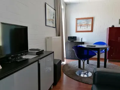 a living room with a tv and a blue chair at Studio's Park - Heverlee in Leuven