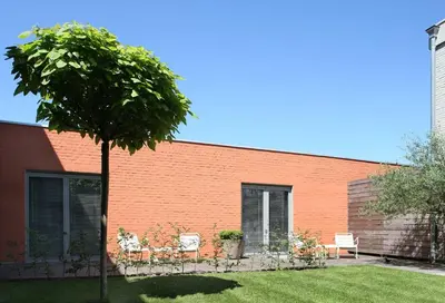 a brick building with two chairs and a tree at midiSud Apartment in Ghent