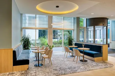 a lobby with tables and chairs and windows at Radisson Hotel Brussels Centre Midi in Brussels