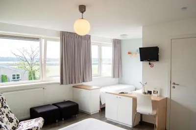 a room with a bed and a desk and a window at LOGIES Tuin der Zinnen in Rijkevorsel