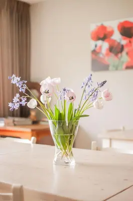 a glass vase filled with flowers on a table at LOGIES Tuin der Zinnen in Rijkevorsel