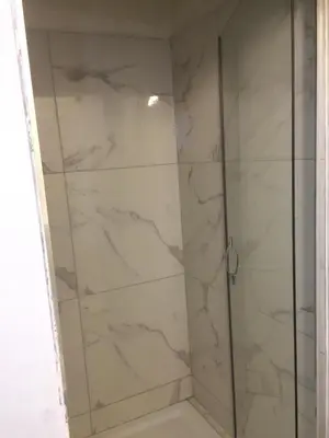 a shower with white marble walls and a glass door at Albert gare du Midi , 29 in Brussels