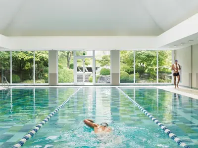 a man swimming in a swimming pool at Aspria Royal La Rasante Hotel & Spa in Brussels