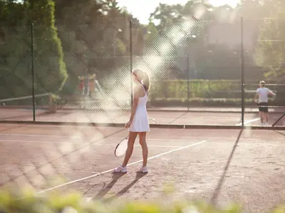 a little girl holding a tennis racket on a tennis court at Aspria Royal La Rasante Hotel & Spa in Brussels