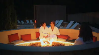 a man and woman sitting on a fire pit at Aspria Royal La Rasante Hotel & Spa in Brussels