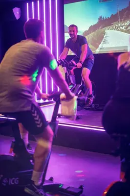 two men riding bikes in front of a tv at Aspria Royal La Rasante Hotel & Spa in Brussels