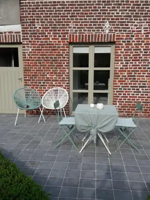 a patio with a table and chairs in front of a brick building at Mille Étoiles in Moorsel