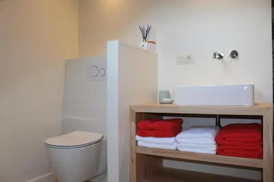 a bathroom with a toilet and towels on a shelf at Mille Étoiles in Moorsel