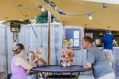 a group of people sitting around a picnic table at Camping Siesta in Lille