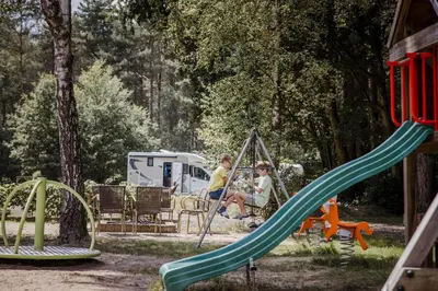 two people sitting on a swing at a playground at Camping Siesta in Lille