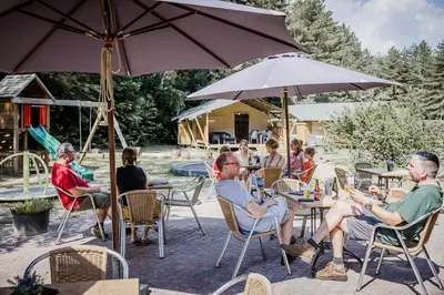 a group of people sitting at tables under an umbrella at Camping Siesta in Lille