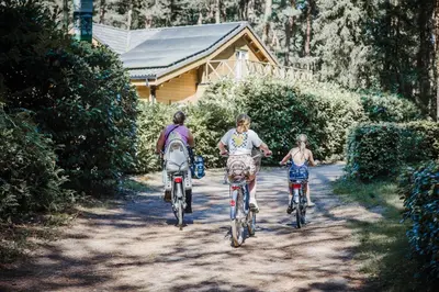three people riding bikes down a dirt road at Camping Siesta in Lille