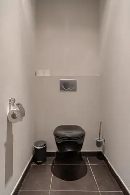 a bathroom with a black toilet in a stall at De Vesten Comfort Lodge in Laakdal