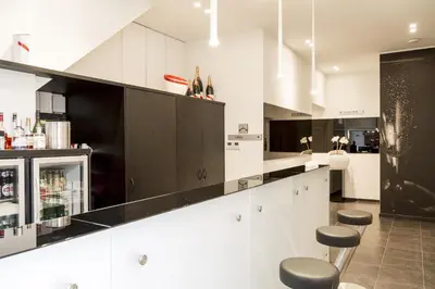 a kitchen with black and white cabinets and stools at Zimmerhof Hotel in Lier