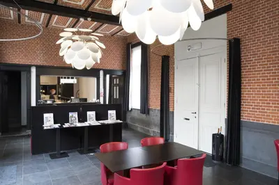 a restaurant with red chairs and a table and a chandelier at Zimmerhof Hotel in Lier