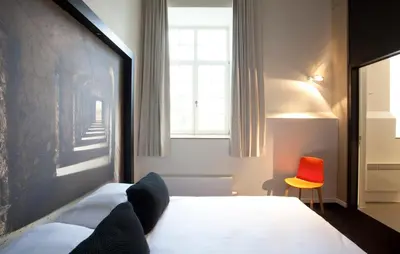 a bedroom with a bed and a red chair at Hotel The Lodge Vilvoorde in Vilvoorde