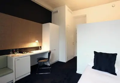 a bedroom with a bed and a desk and a chair at Hotel The Lodge Vilvoorde in Vilvoorde