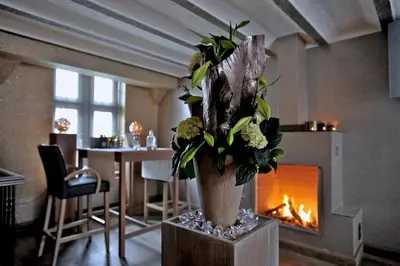 a vase with flowers on a table next to a fireplace at Suite & B by Hofke van Bazel in Bazel