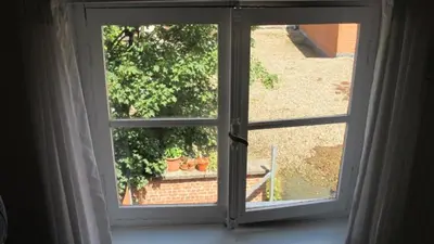 an open window with a view of a garden at Huize Maeterlinck in Ghent