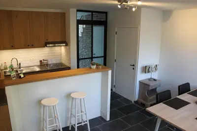 a kitchen with a counter and stools and a table at Logies Tommenmolen in Grimbergen