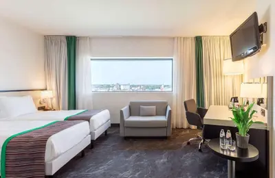 a hotel room with a bed and a chair and a television at Park Inn by Radisson Leuven in Leuven